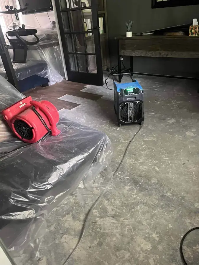Air movers and a dehumidifier on plastic-covered flooring during a Blue Springs dry-out