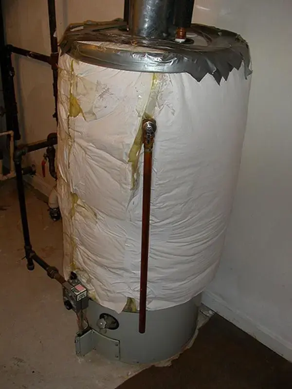 Rusted, leaking water heater with water stains down the tank jacket in a Blue Springs basement